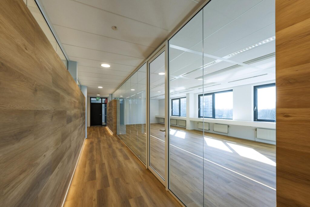 Modern office hallway with wooden flooring and glass walls at Prof. W.H. Keesomlaan.